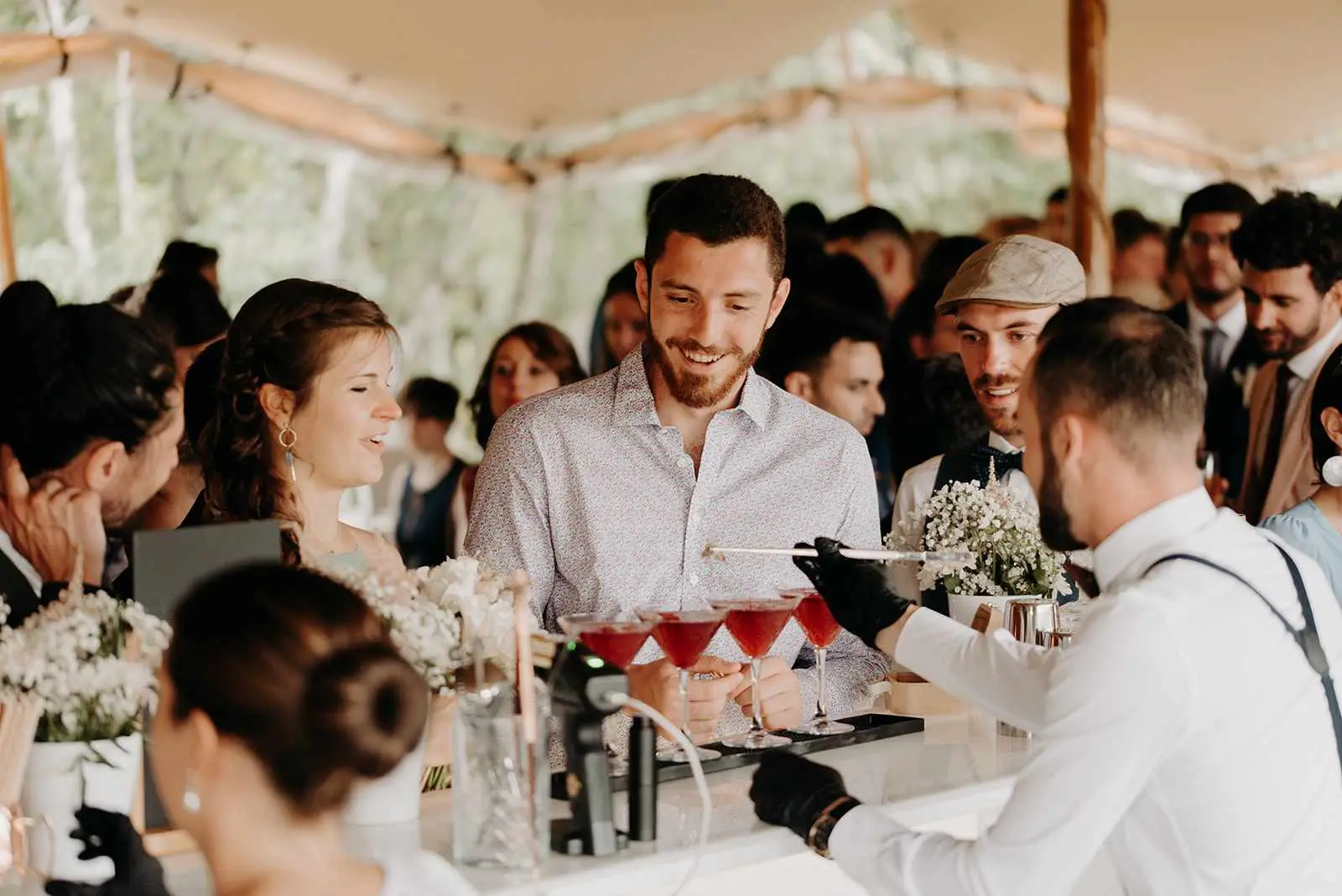 Barman qui confectionne un cocktail derrière son bar blanc lors d"un mariage