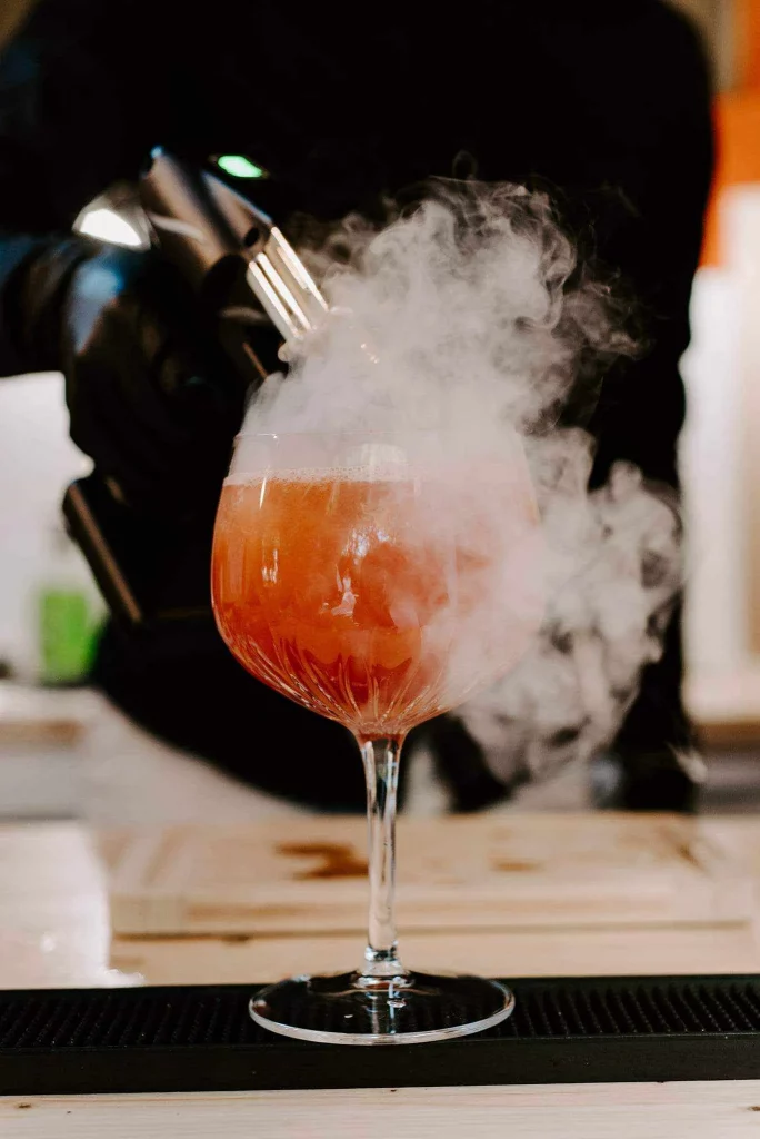 Cocktail orangé dans un verre à gin avec de la fumée