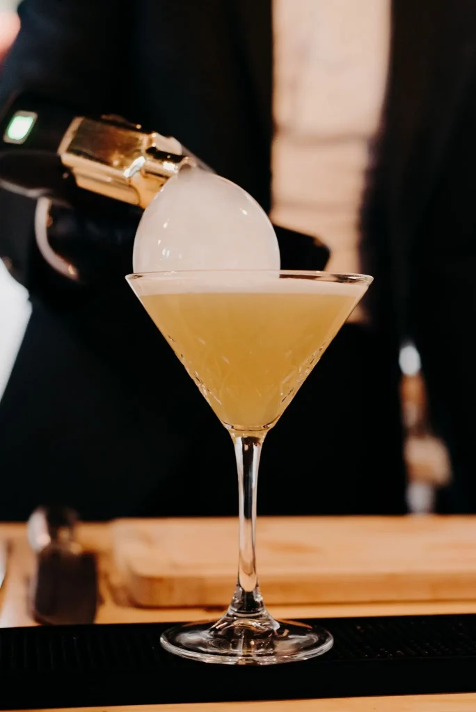 Cocktail jaune dans un verre à martini avec une bulle de fumée au dessus